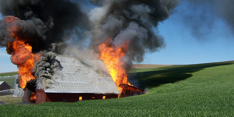 Barn on fire in a field