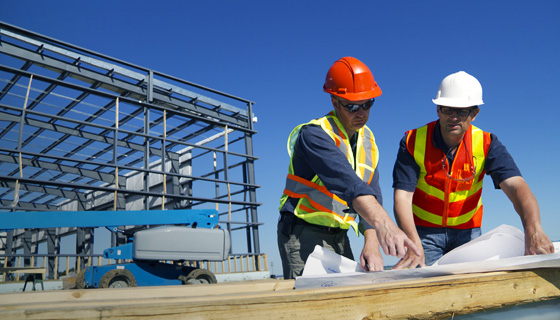 Two contruction workers going over plans on site
