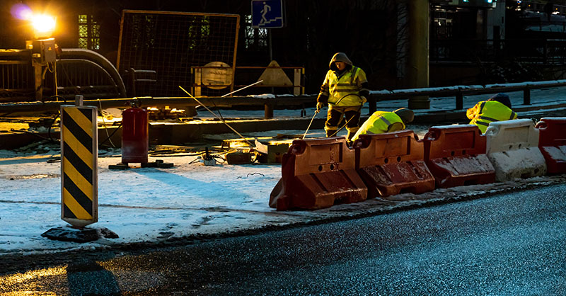 Construction workers doing work on snowy roads